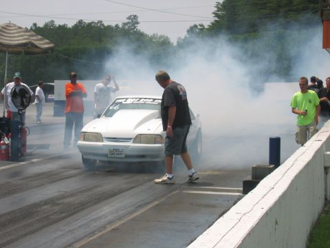 1992 Ford Mustang - A white 1992 Ford Mustang performs a burnout on a drag strip, generating a large cloud of smoke.