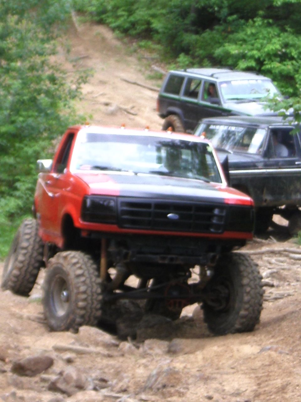 Red 1994 Ford F-250 with lifted suspension on a rocky trail