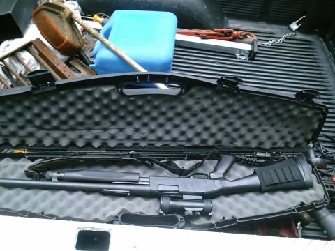 2001 Dodge 2500 - A shotgun is secured in a padded case within the bed of a pickup truck, alongside various tools and a blue gas can.