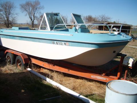 1988 Chevrolet Suburban - A boat sits on a trailer in a dry, grassy area with trees in the background.