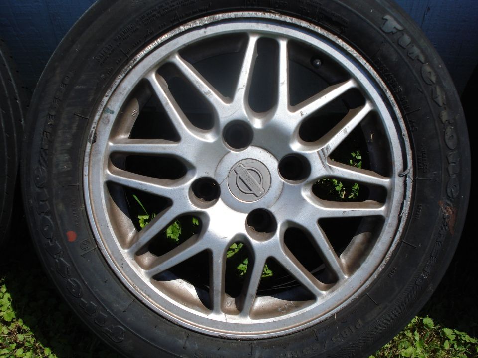 Close-up of a Nissan alloy wheel with a Firestone tire. The wheel has a Nissan logo in the center