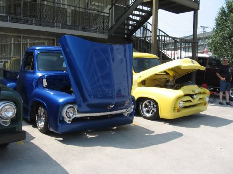 1966 Ford F-100 - Blue and yellow Ford F-series trucks parked side-by-side with their hoods raised.