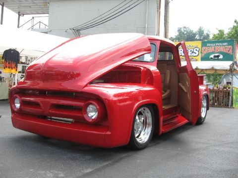 1966 Ford F-100 - A bright red custom pickup truck is displayed with its hood and driver's side door open.