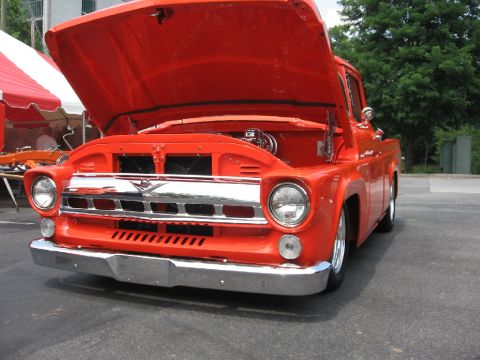 1966 Ford F-100 - This bright orange 1956 Ford F-100 pickup truck is displayed with its hood open, revealing the engine compartment.