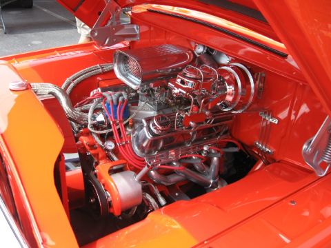 1966 Ford F-100 - Custom V8 engine bay with polished chrome components and bright red accents.