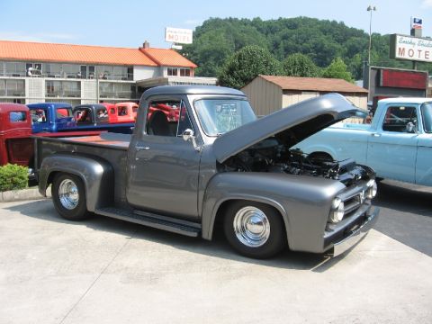 1966 Ford F-100 - A row of colorful Ford F-series trucks are parked outside a motel.