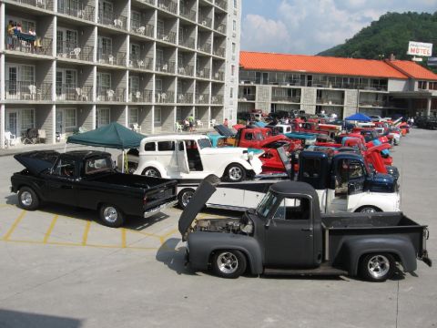 1966 Ford F-100 - A collection of vintage trucks are gathered in a parking lot with a motel in the background.
