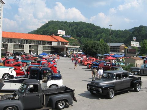 1966 Ford F-100 - A gathering of classic pickup trucks, including a prominent 1956 Ford F-100, fills a motel parking lot under a sunny sky.