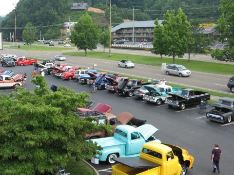 1966 Ford F-100 - A gathering of vintage trucks and cars fills a parking lot, with several vehicles displaying their engines.