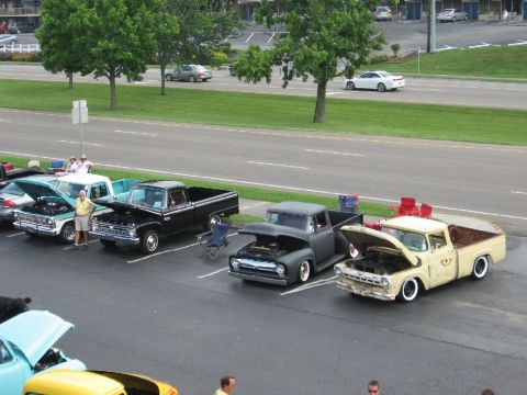 1966 Ford F-100 - Several classic Ford F-series trucks are parked in a lot, some with hoods open.