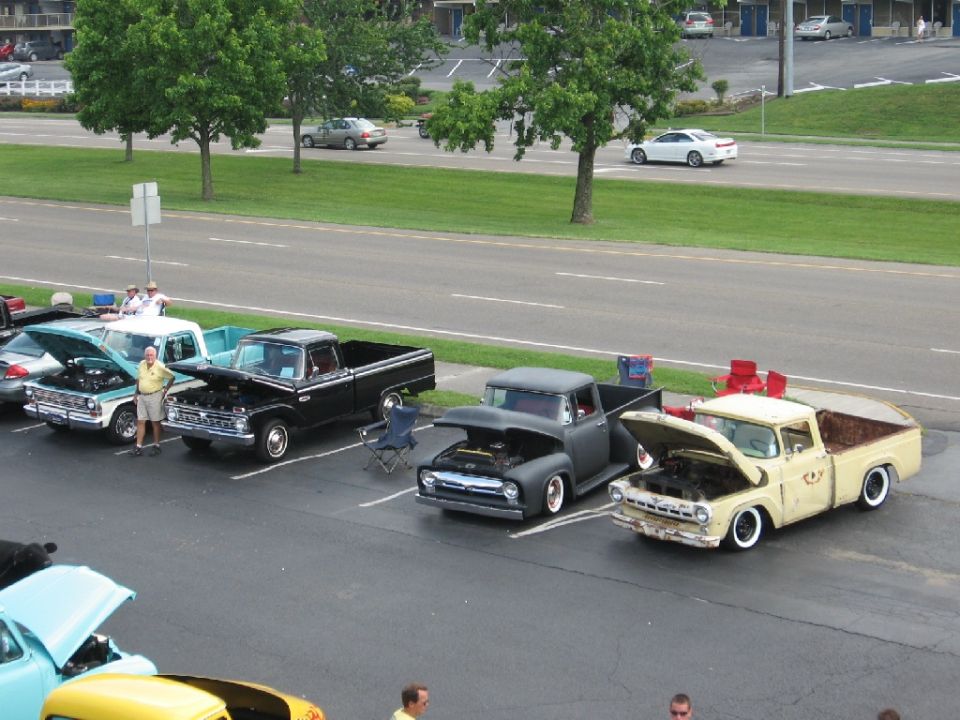Yellow Ford F-series truck with hood open, parked in a lot