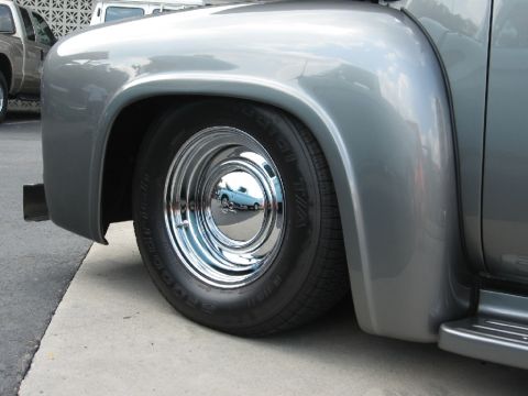 1966 Ford F-100 - Front fender and wheel of a classic Ford F-series truck, with a reflection of another vehicle in the hubcap.