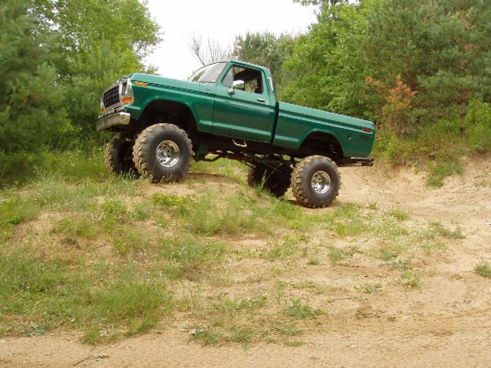 Green 1979 Ford F-100 pickup truck with large tires on a dirt hill