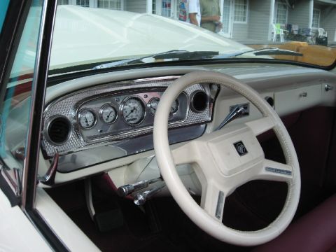 1966 Ford F-100 - The interior of a classic vehicle features a custom dashboard with multiple gauges and a cream-colored steering wheel.
