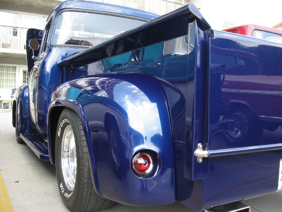 Blue pickup truck rear quarter panel with custom spoiler and chrome wheels. BFGoodrich tires visible