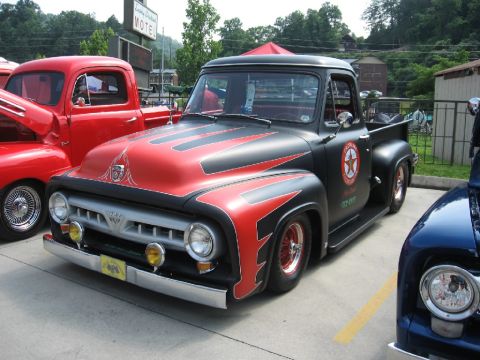 1966 Ford F-100 - Customized Ford F-series truck with distinctive red and black flame paint scheme and chrome accents.