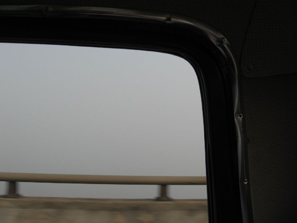 View from inside a vehicle, looking out the window at a foggy landscape with a guardrail