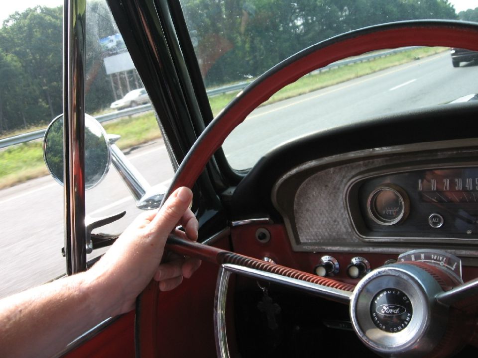 Driver's hand on the steering wheel of a 1966 Ford F-100, dashboard visible