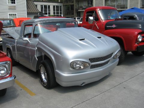 1966 Ford F-100 - A modified pickup truck with a unique front end is parked next to a red truck.