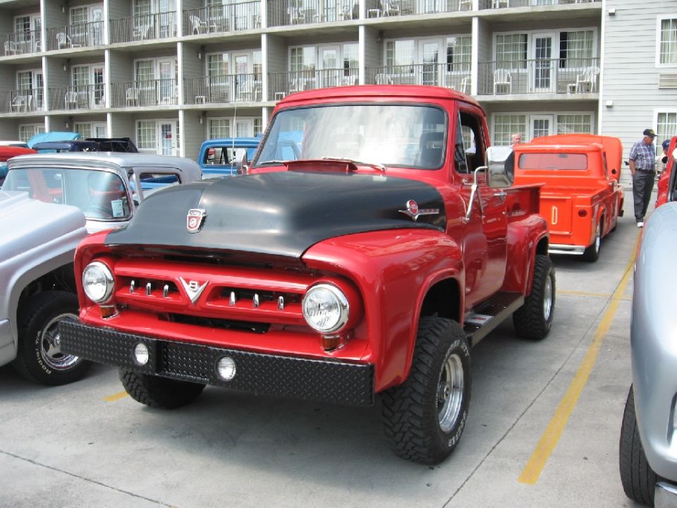 Red pickup truck with black hood and diamond plate bumper. Tires read 'Radial'