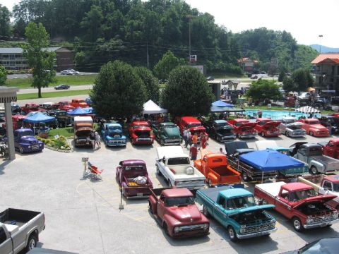 1966 Ford F-100 - A gathering of vintage pickup trucks is displayed outdoors, with a swimming pool visible in the background.