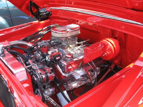 1966 Ford F-100 - Close-up of a polished V8 engine in a red vehicle's engine bay.