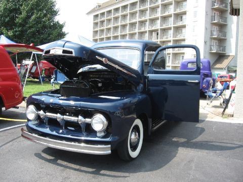 1966 Ford F-100 - Dark blue 1951 Ford F-series truck with hood open, parked next to a purple truck.