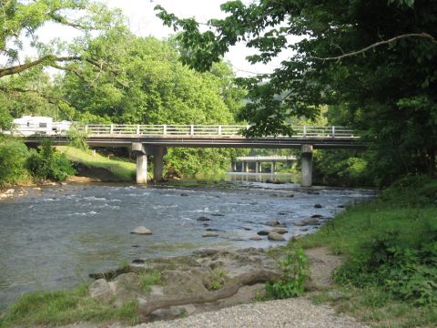 1966 Ford F-100 - A scenic view of a river flowing under a bridge, with two RVs crossing the bridge.