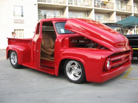 1966 Ford F-100 - This red 1956 Ford F-100 pickup truck features a custom tan interior and chrome wheels, with its hood open to reveal the engine.
