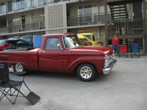 1966 Ford F-100 - A red 1966 Ford F-100 pickup truck is parked next to a yellow truck.