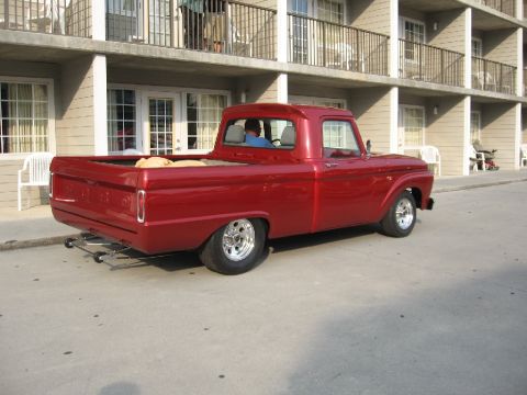 1966 Ford F-100 - A red pickup truck is parked in front of a motel with balconies above.