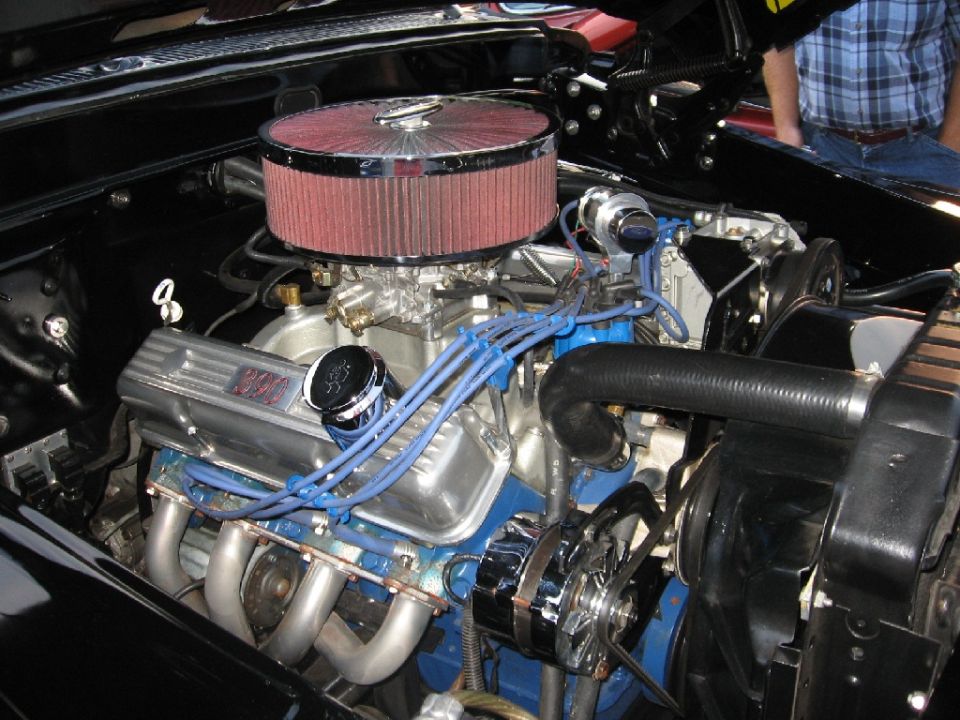 V8 engine bay showing chrome air cleaner, headers, and blue spark plug wires