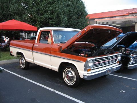 1966 Ford F-100 - A two-tone Ford F-Series truck from the late 1960s is displayed with its engine visible.