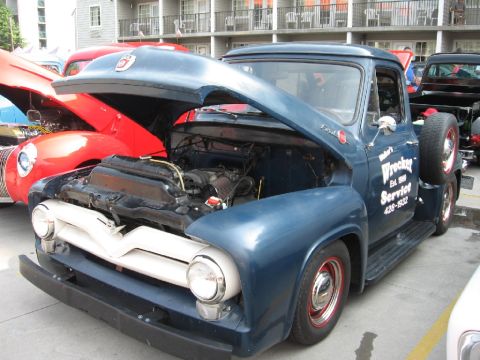 1966 Ford F-100 - A blue 1956 Ford F-100 truck, identified by its distinctive grille and body style, is displayed with its hood open, revealing the engine.
