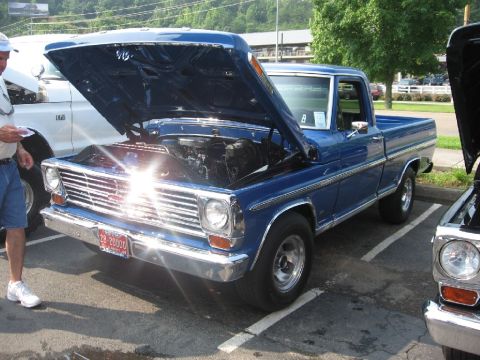 1966 Ford F-100 - A blue pickup truck is parked with its hood open, revealing the engine compartment.