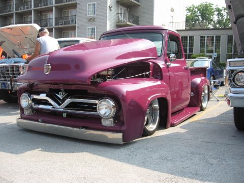 1966 Ford F-100 - A customized purple pickup truck is parked with its hood open, its engine and custom front end.
