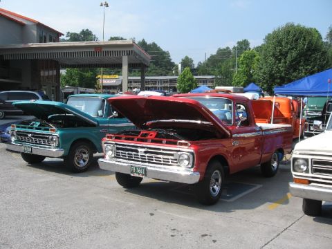 1966 Ford F-100 - Two classic Ford F-100 trucks are displayed with their hoods open at an outdoor event.