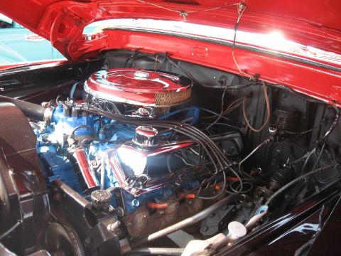 1966 Ford F-100 - The engine bay of a 1966 Ford F-100 shows a V8 engine with chrome accents and bright blue valve covers.