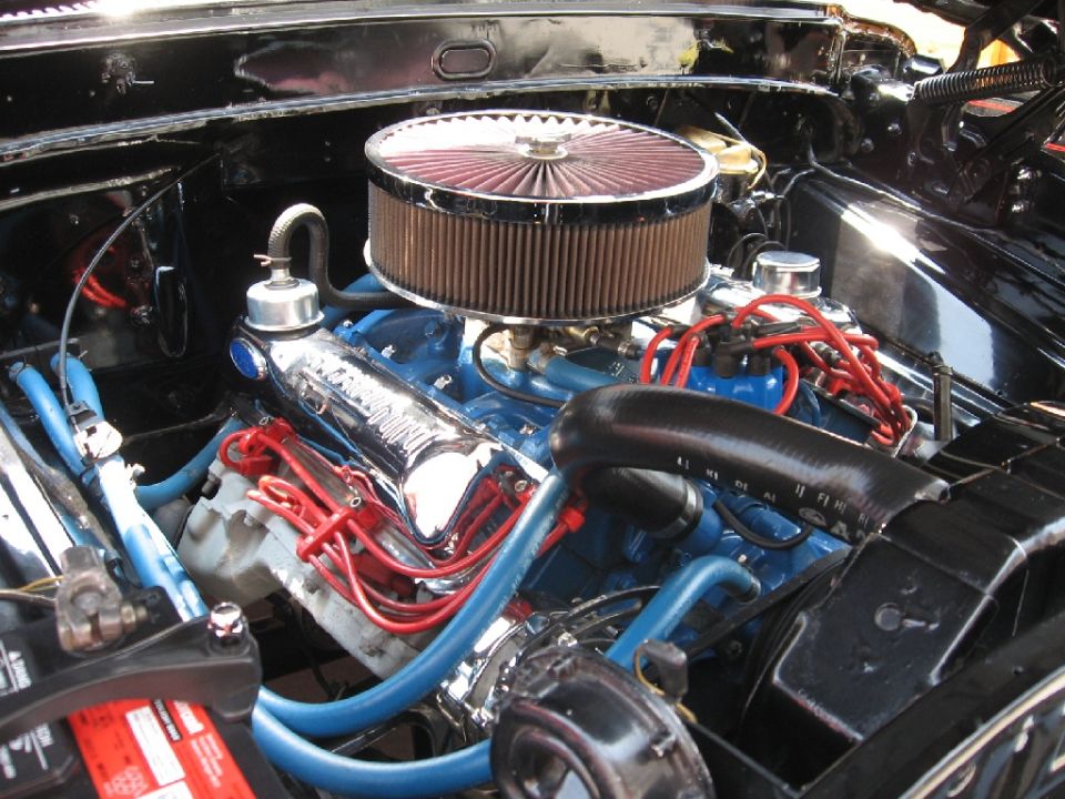 Engine bay with blue engine block, chrome valve covers, and red spark plug wires