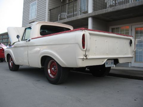 1966 Ford F-100 - Rear view of a cream-colored 1965 Ford F-100 pickup truck with red trim and red wheels.