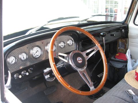 1966 Ford F-100 - The interior of a 1966 Ford F-100 features a classic wooden steering wheel and a custom gauge cluster.