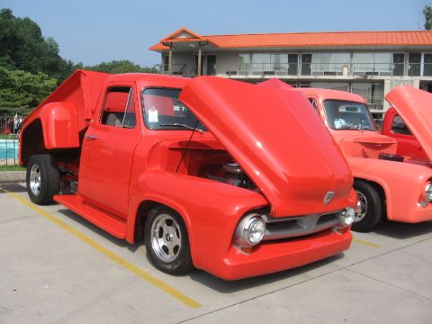 1966 Ford F-100 - Two red pickup trucks are parked side-by-side with their hoods open, displaying their engines.
