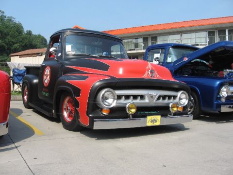 1966 Ford F-100 - Customized black and red Ford pickup truck with flames, parked next to a blue Ford pickup.