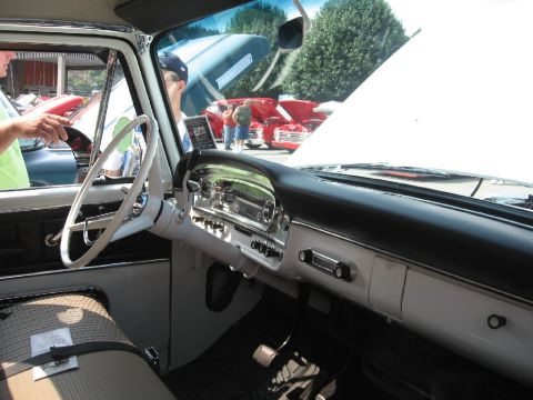 1966 Ford F-100 - View from inside a vintage truck, showing the dashboard and steering wheel, with other cars in the background.