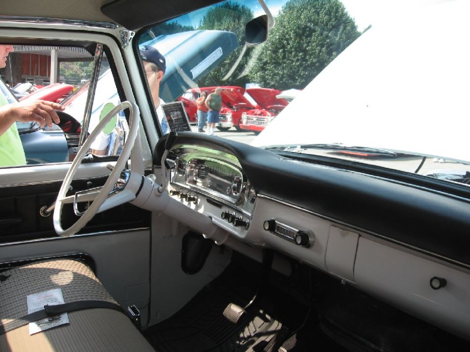 Dashboard and steering wheel of a classic truck, with other vehicles visible outside
