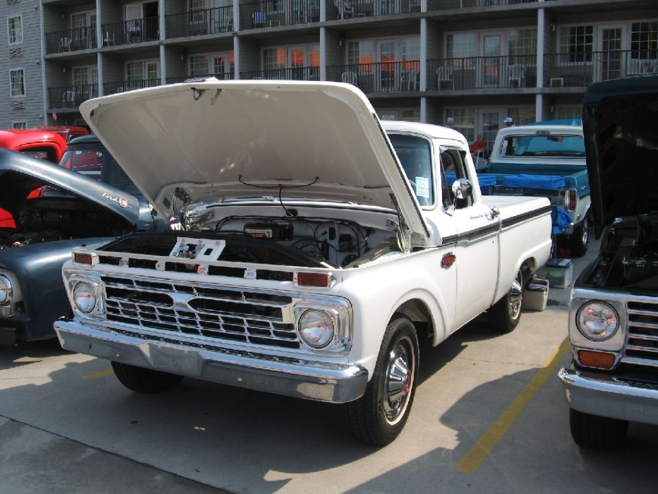 White 1965 Ford F-100 truck with hood open, parked outdoors