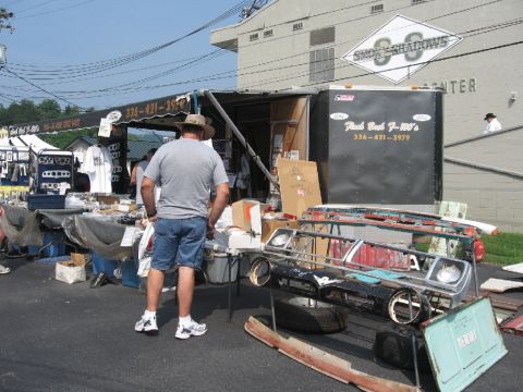 1966 Ford F-100 - A collection of vehicle parts is displayed for sale at an outdoor event.