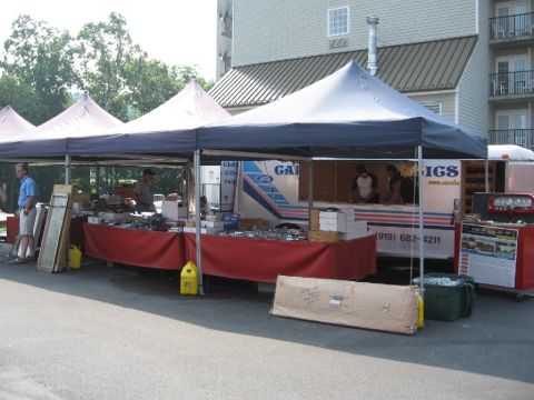 1966 Ford F-100 - Outdoor market stall displaying various automotive parts and accessories under tents.
