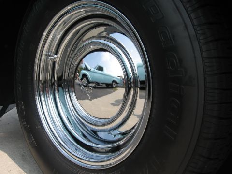 1966 Ford F-100 - Reflection in a chrome hubcap shows a light blue pickup truck and another vehicle.