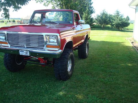 1978 Ford Bronco - This lifted pickup truck features a prominent chrome grille and large off-road tires.